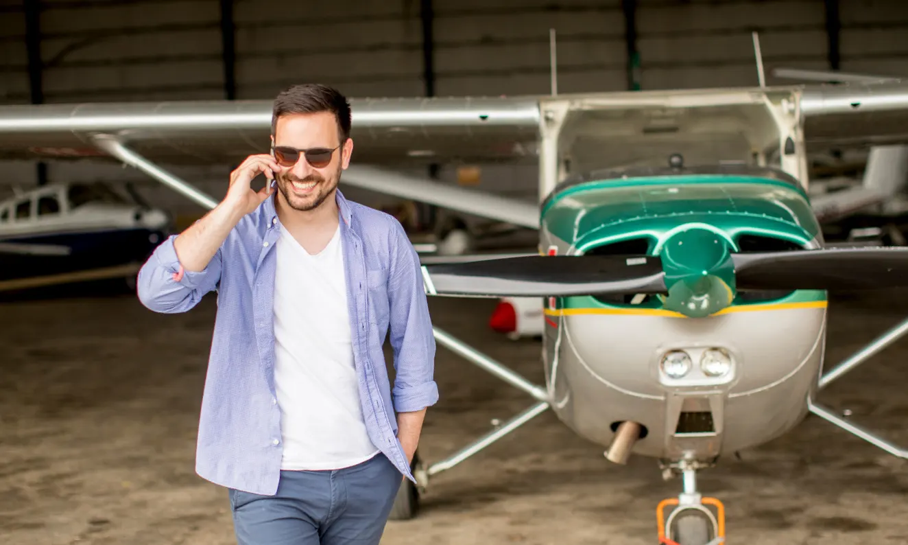 Flight instructor answering a call beside a single-engine training aircraft