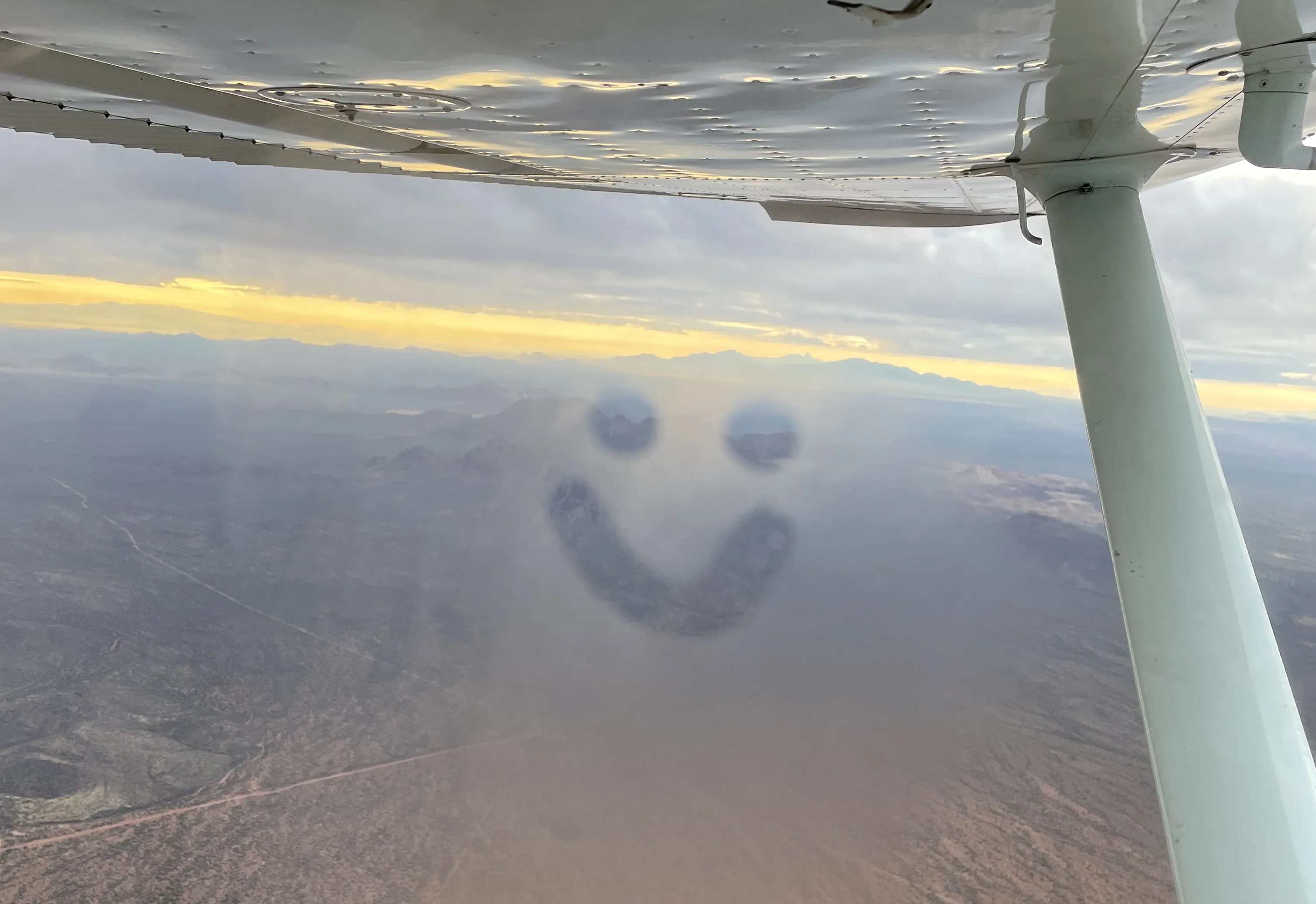 Smiley face through the fog on the window of a SimpliFly plane over the Phoenix Valley